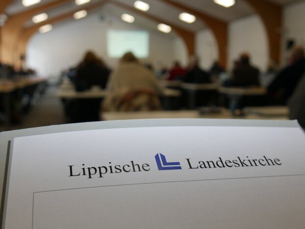 Blick in den Synodensaal der Lippischen Landessynode. Im Vordergrund liegt ein Schriftstück