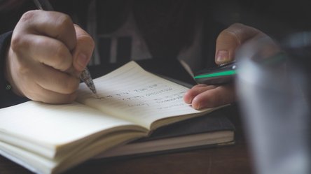 In ein Notizbuch erfolgen handschriftliche Eintragungen