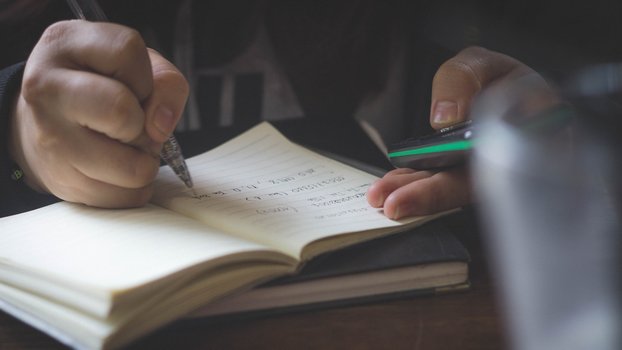 In ein Notizbuch erfolgen handschriftliche Eintragungen